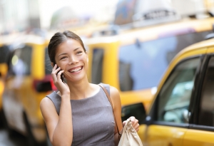Business woman on smart phone in New York City, Manhattan walking in dress suit holding doggy bag smiling and laughing, Young multiracial Asian Caucasian professional female businesswoman in her 20s.