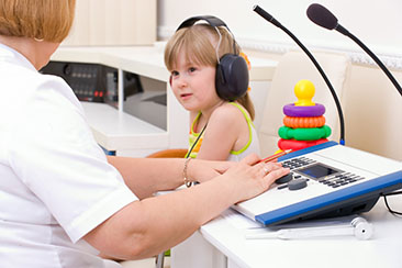 Girl in yellow shirt taking hearing test.