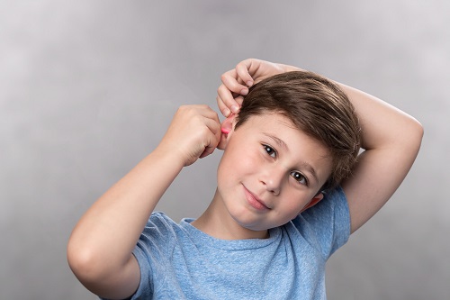 Little boy inserting formable earplug