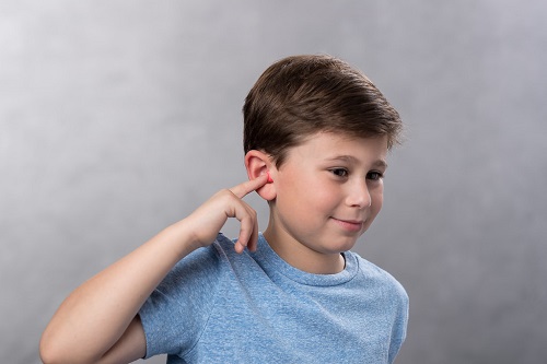 Young boy holding foam earplug in place in his ear to give it time to expand.