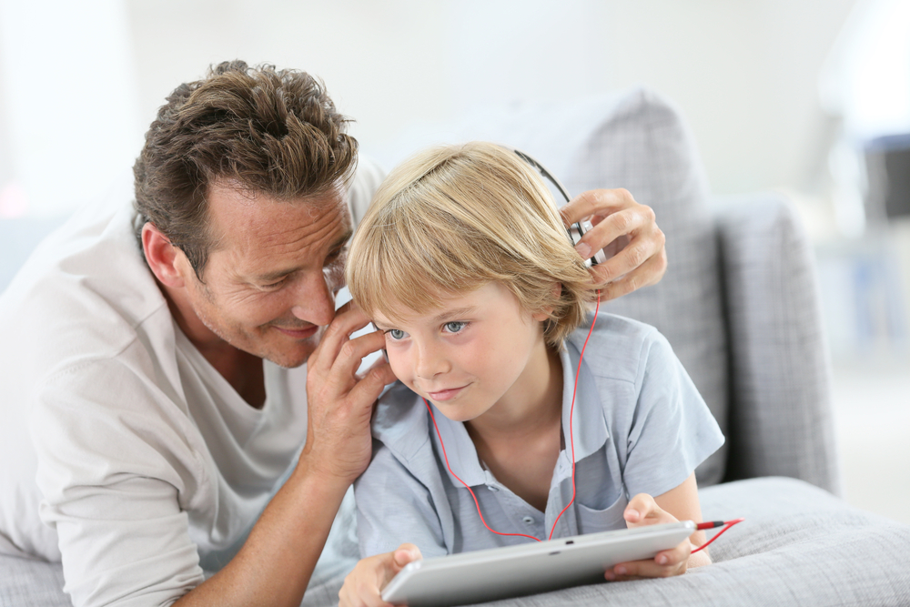 Man checking the headphones of a child. 