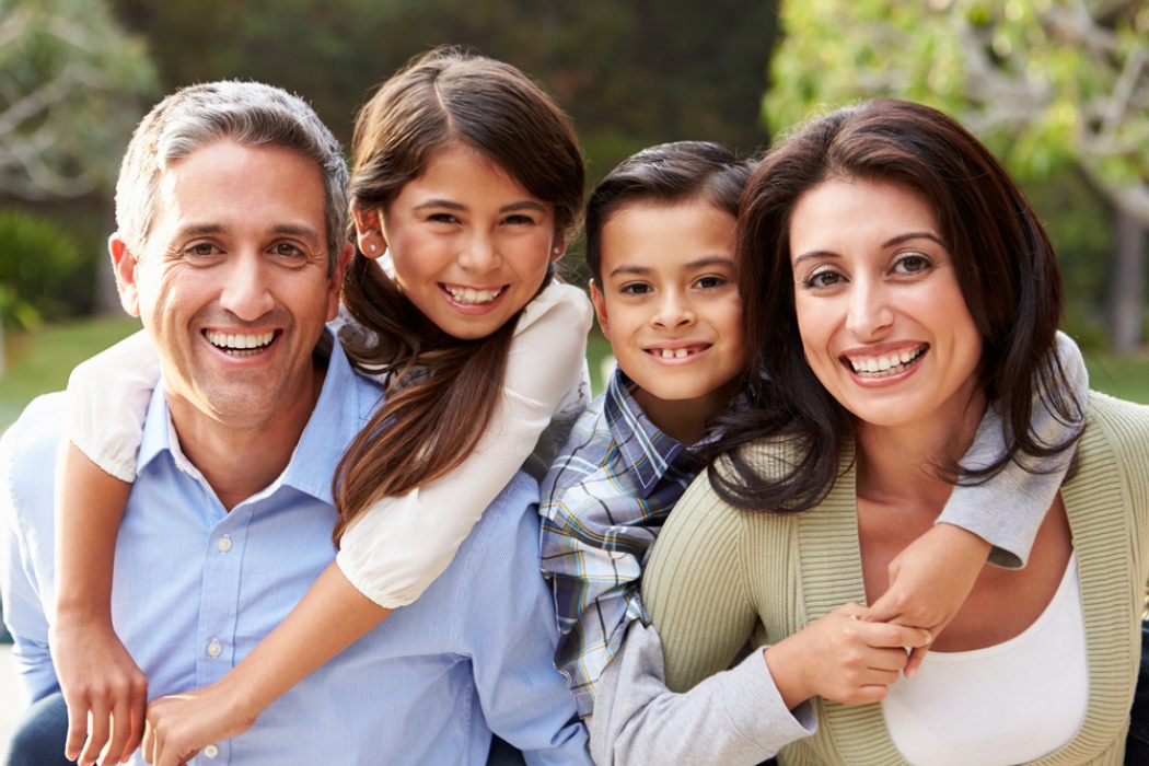 Un padre, una madre, hijo e hija sonriendo.