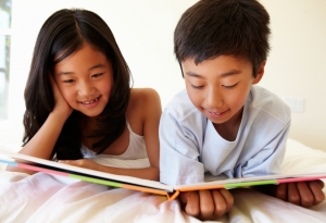 Children sitting on bed reading a book