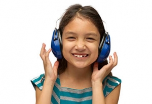 Una niña sonríe y usa orejeras con protección auditiva.
