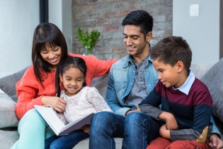 Una familia sentada en el sofá leyendo un libro.