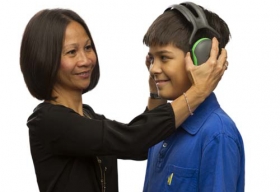 Una mujer le pone protectores de oído a un niño.