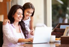 Una mujer y un niña mirando la pantalla de la computadora.